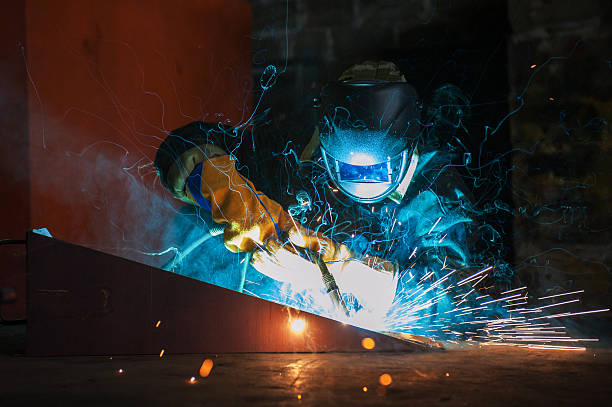 worker welding metal with sparks at factory