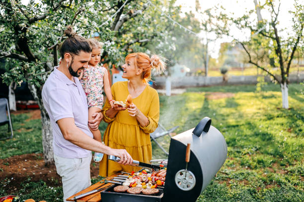 Family preparing meal in backyard on barbecue grill